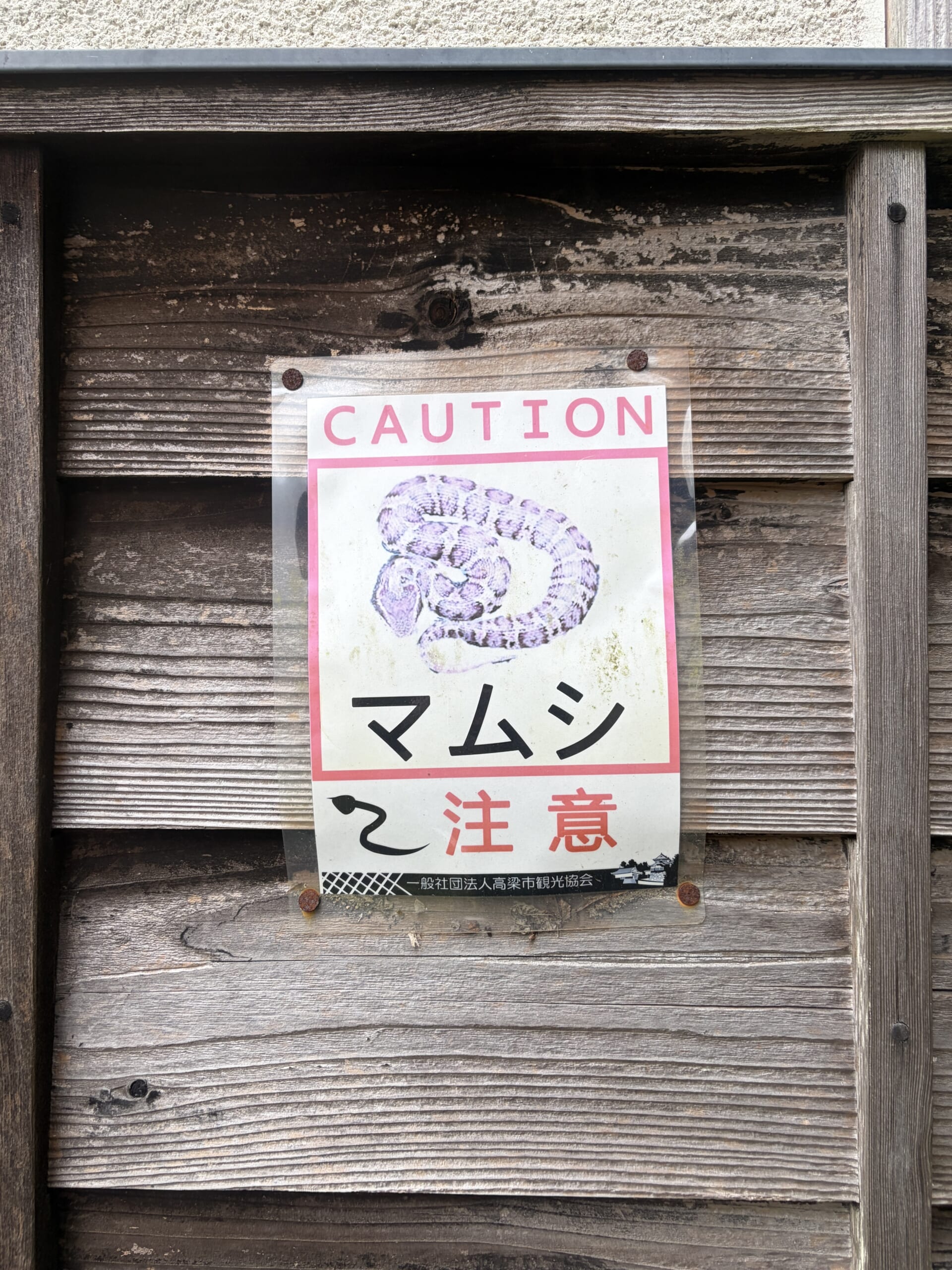木の壁に貼られたマムシ注意の表示